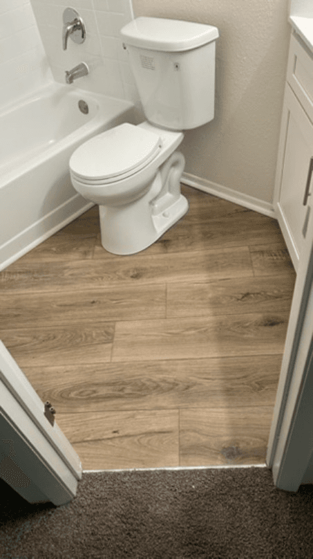 Warm wood-look luxury vinyl plank in a bathroom around the tub and toilet