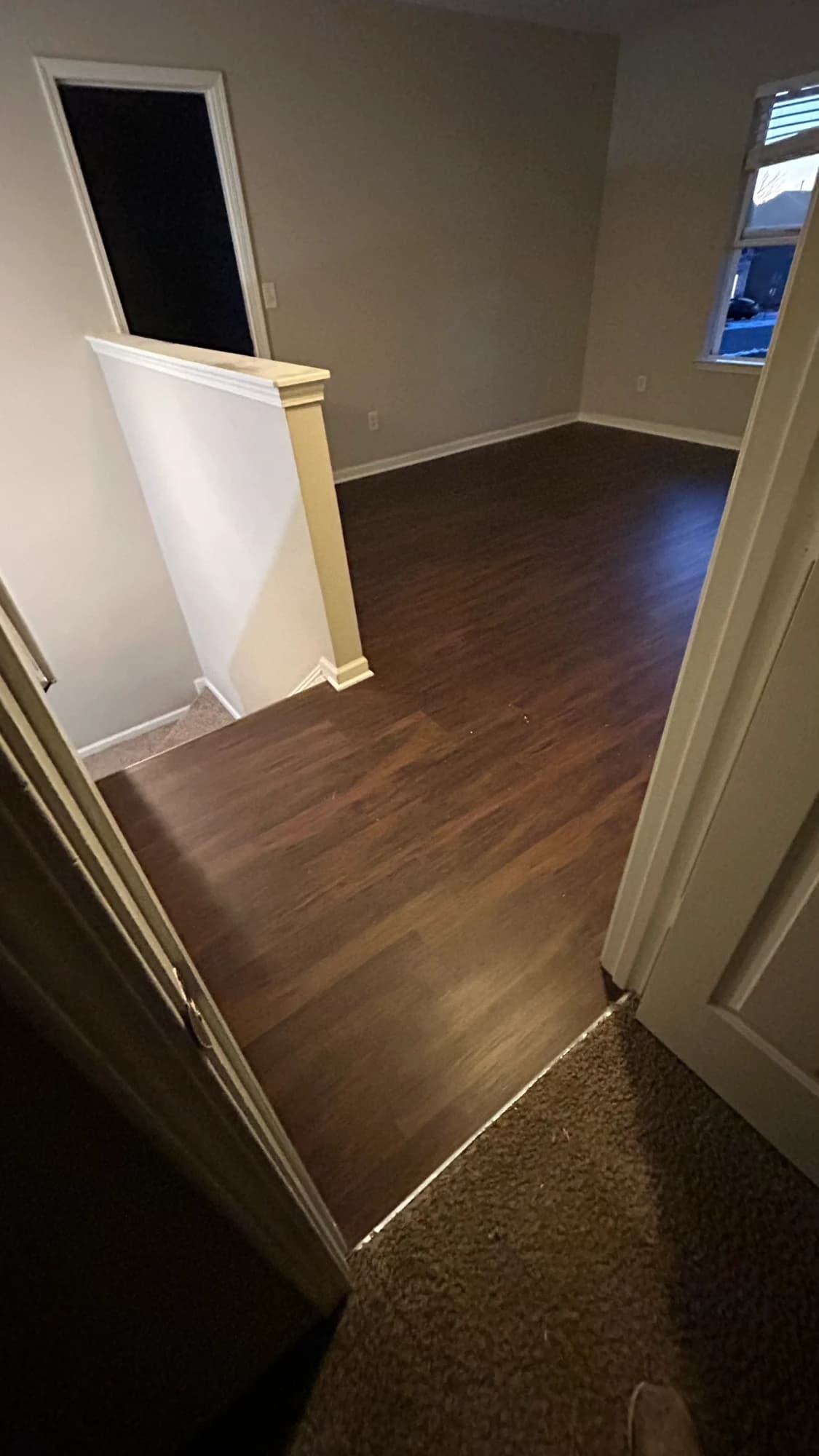 Espresso-toned plank flooring at a stair landing meeting carpet