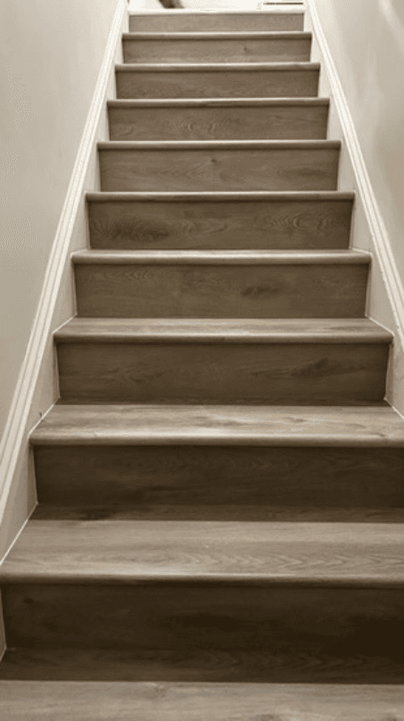 Grey oak luxury vinyl plank wrapping a full staircase, installed by Randol Perez